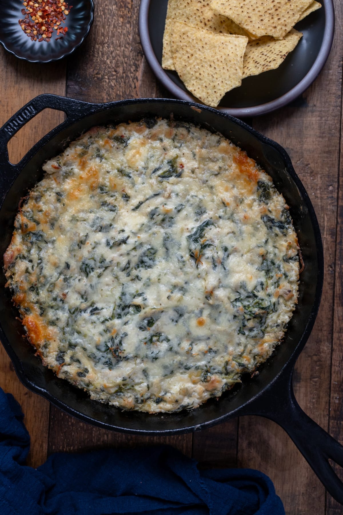Spinach artichoke dip in skillet with tortilla chips on the side.