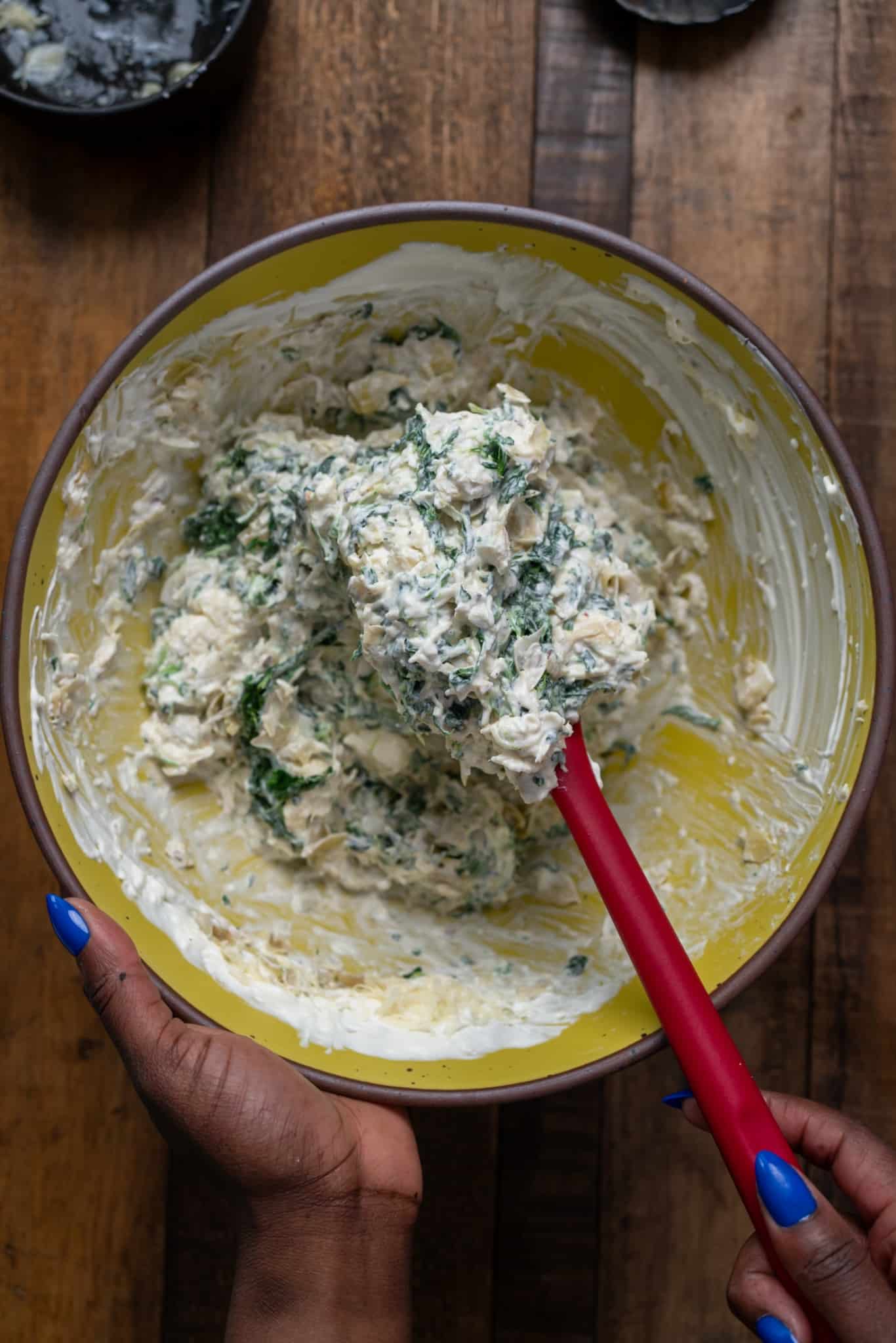 miced cheeses and spinach and artichoke in bowl on spoon