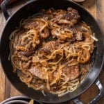 Liver and onions in skillet with salt and pepper on side