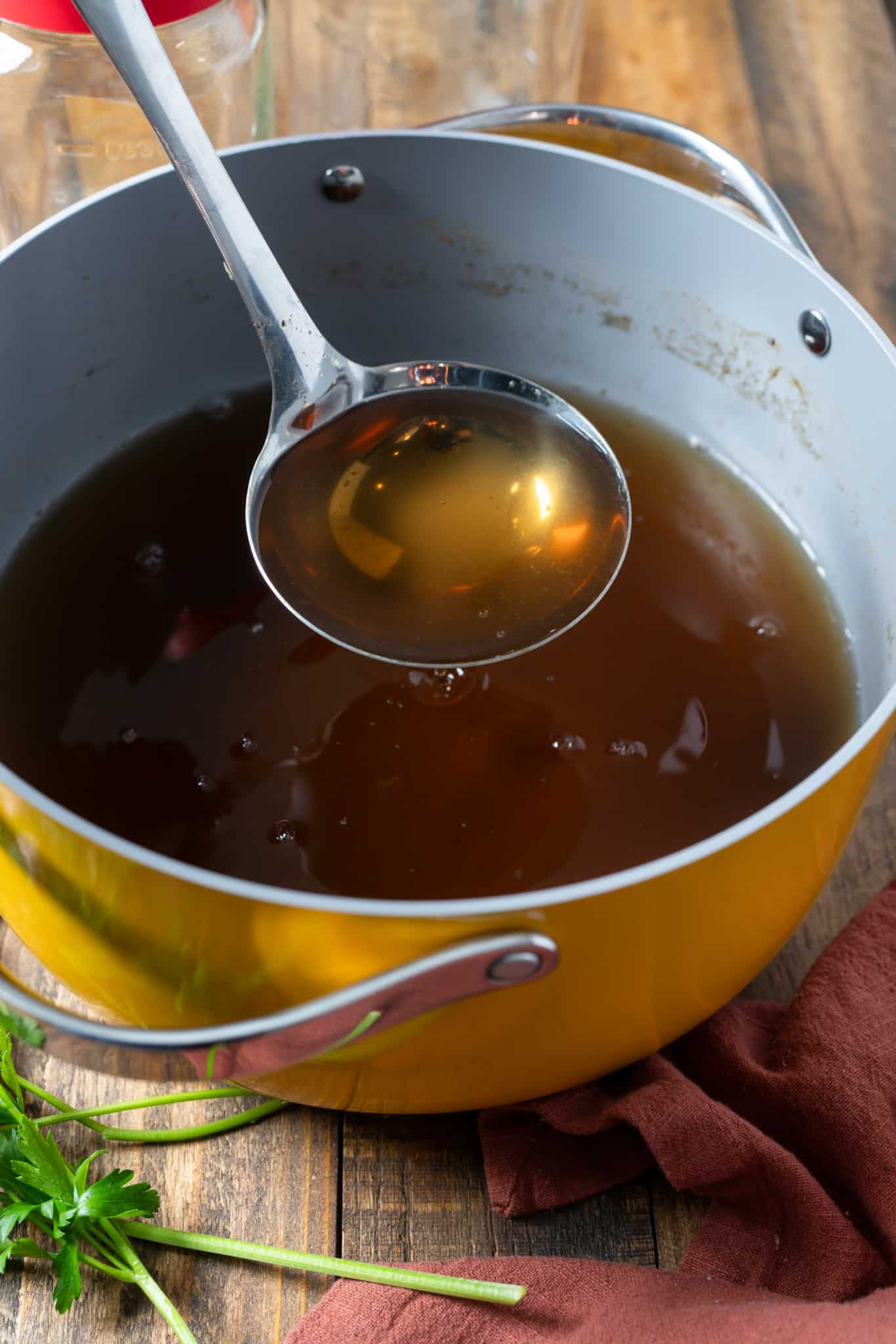 strained vegetable broth being lifted with spoon out of pot