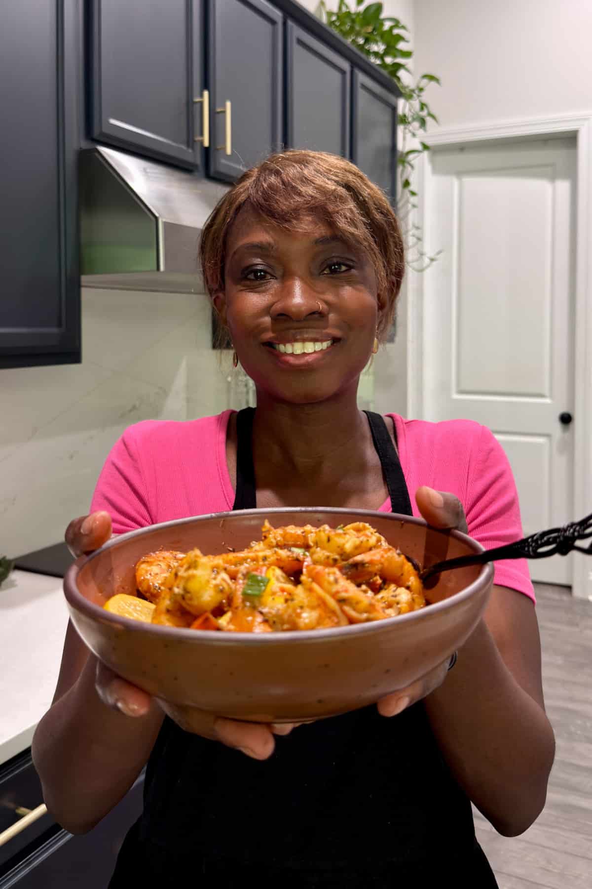 Tanya holding a bowl of BBQ shrimp and looking at the camera smiling