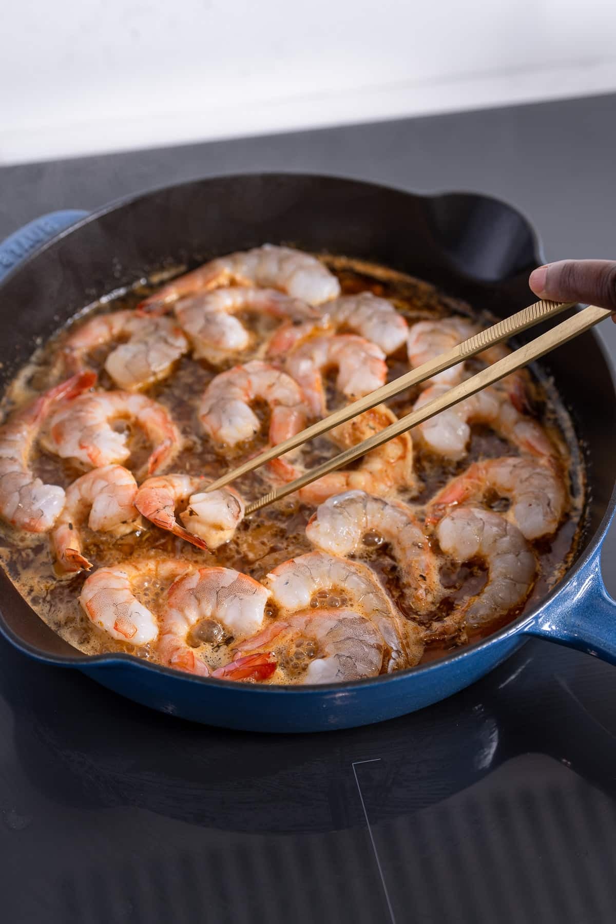 Shrimp cooking in skillet and sauce for barbecue shrimp.
