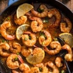 New Orleans-style BBQ shrimp in a skillet with a spoon and bread surrounding it
