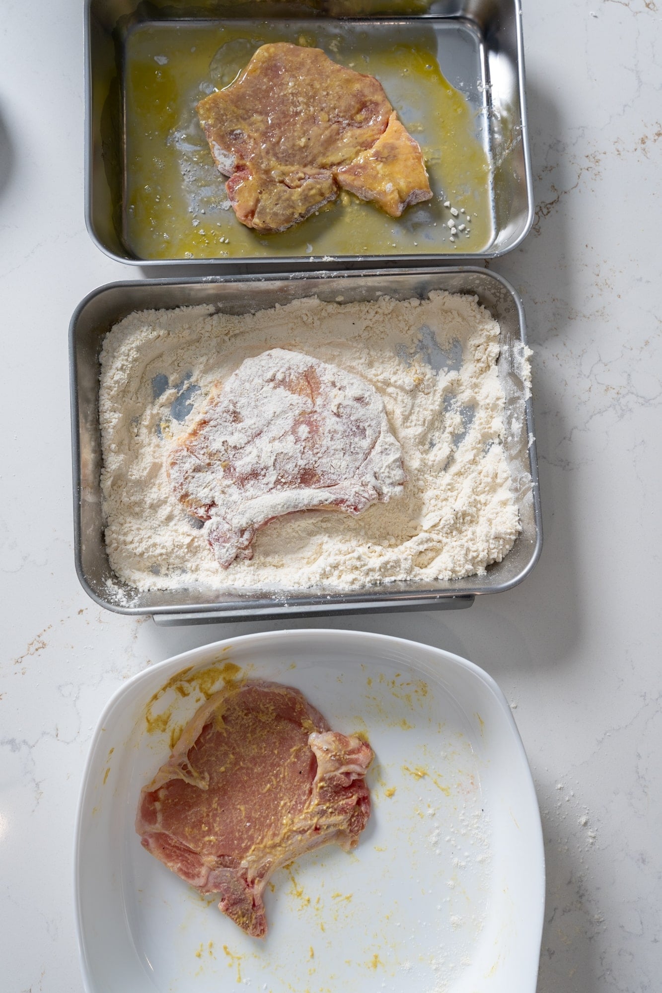 Battering station for pork chops with flour and egg wash.
