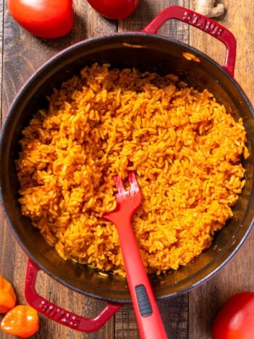 jollof rice in pot surrounded by tomatoes