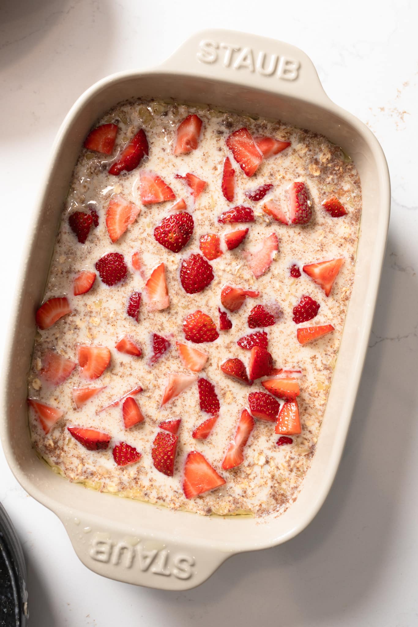 Wet ingredients of strawberry baked oatmeal and casserole dish before baking