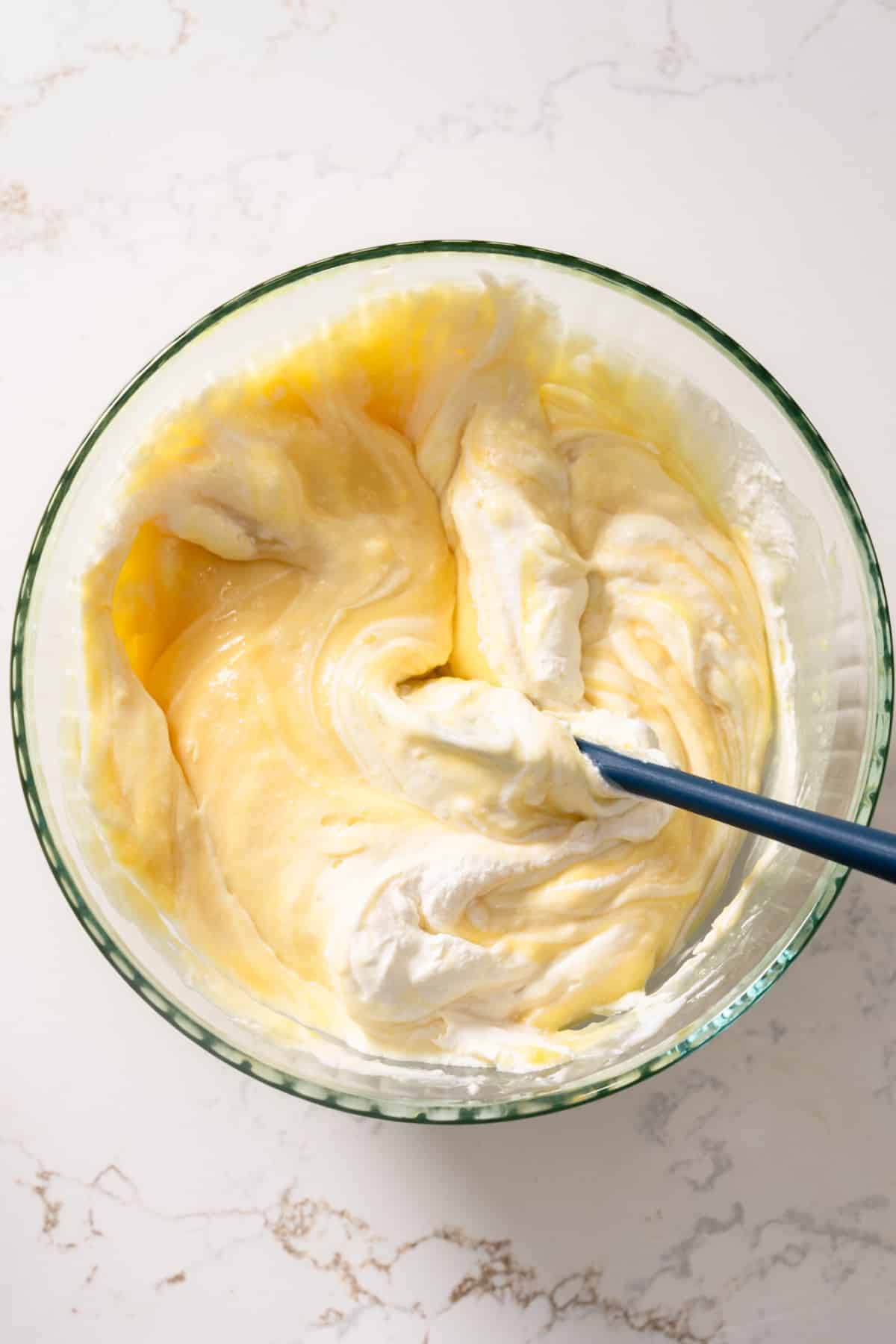 Folding the whipped cream into the vanilla pudding mix in a bowl