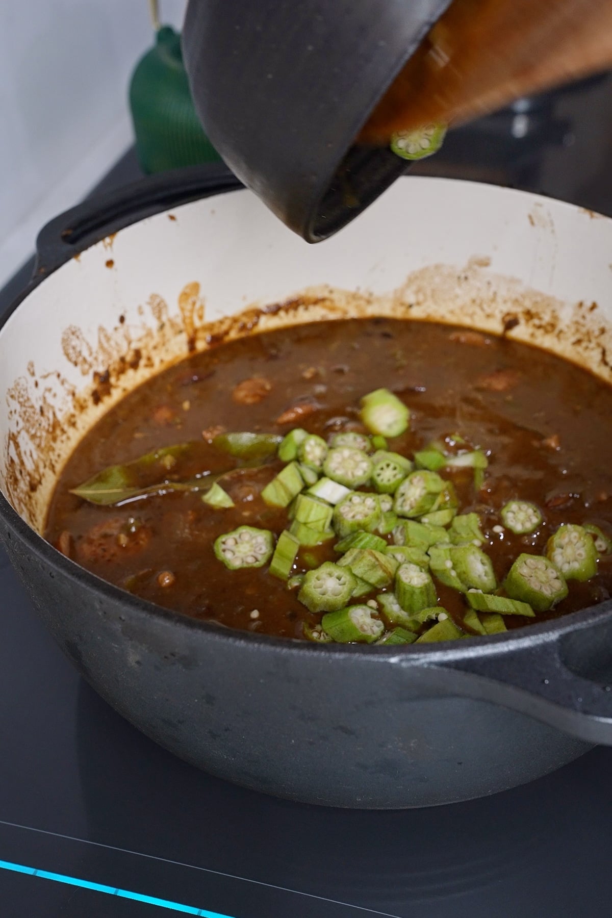 Okra being put in gumbo stew
