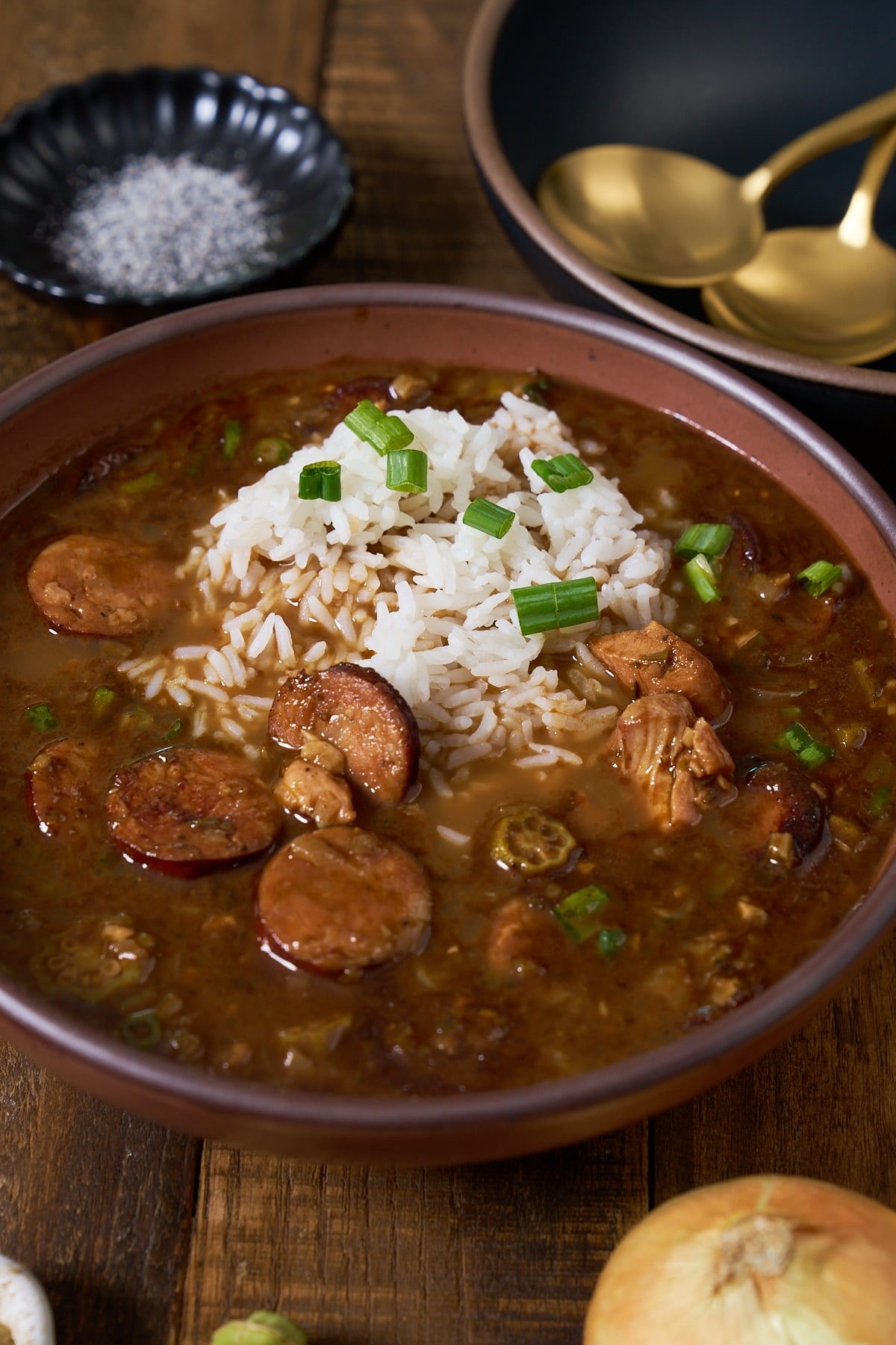 Gumbo in a bowl with rice on top, sprinkled with green onions