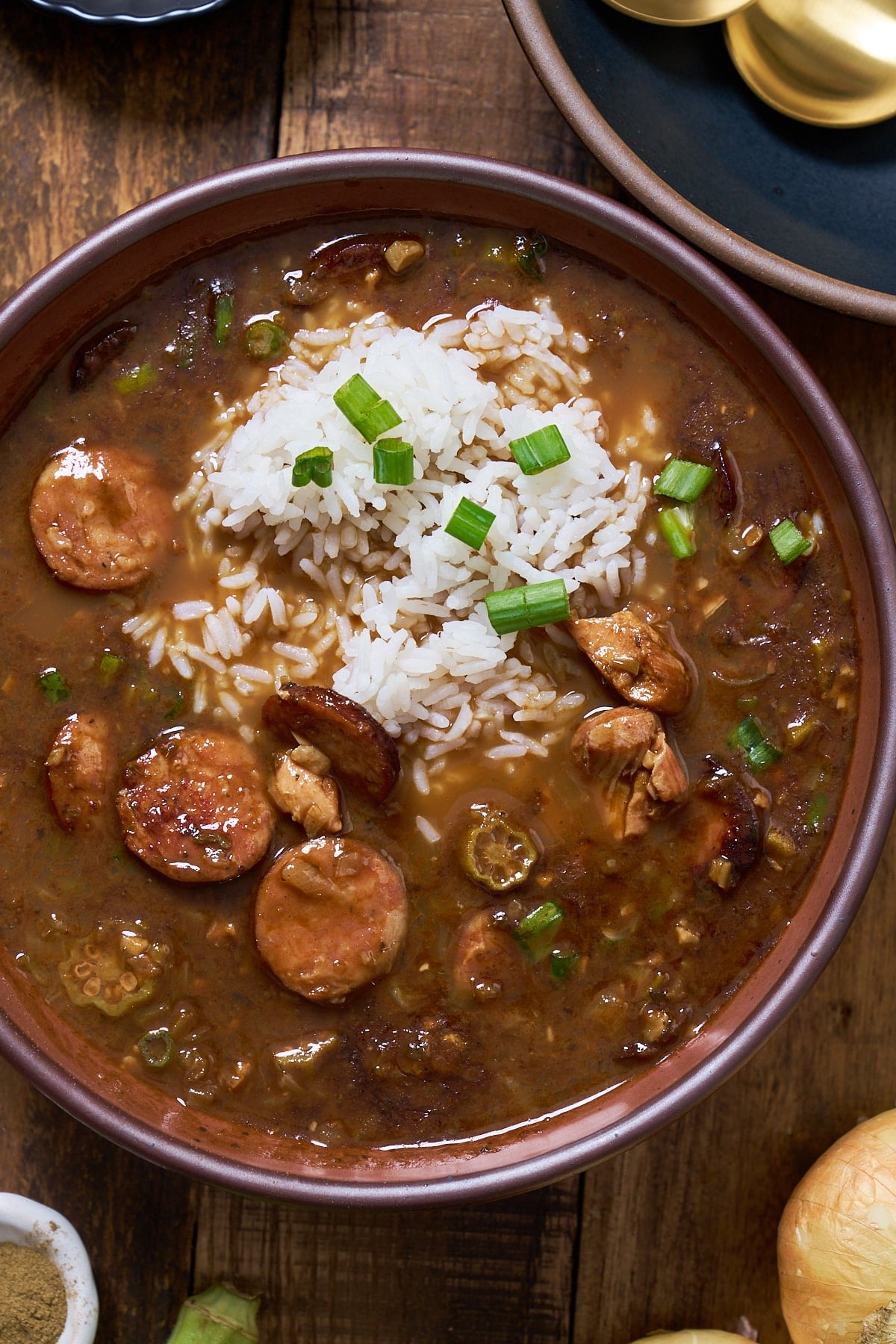 gumbo in a bowl with rice on top with green onions