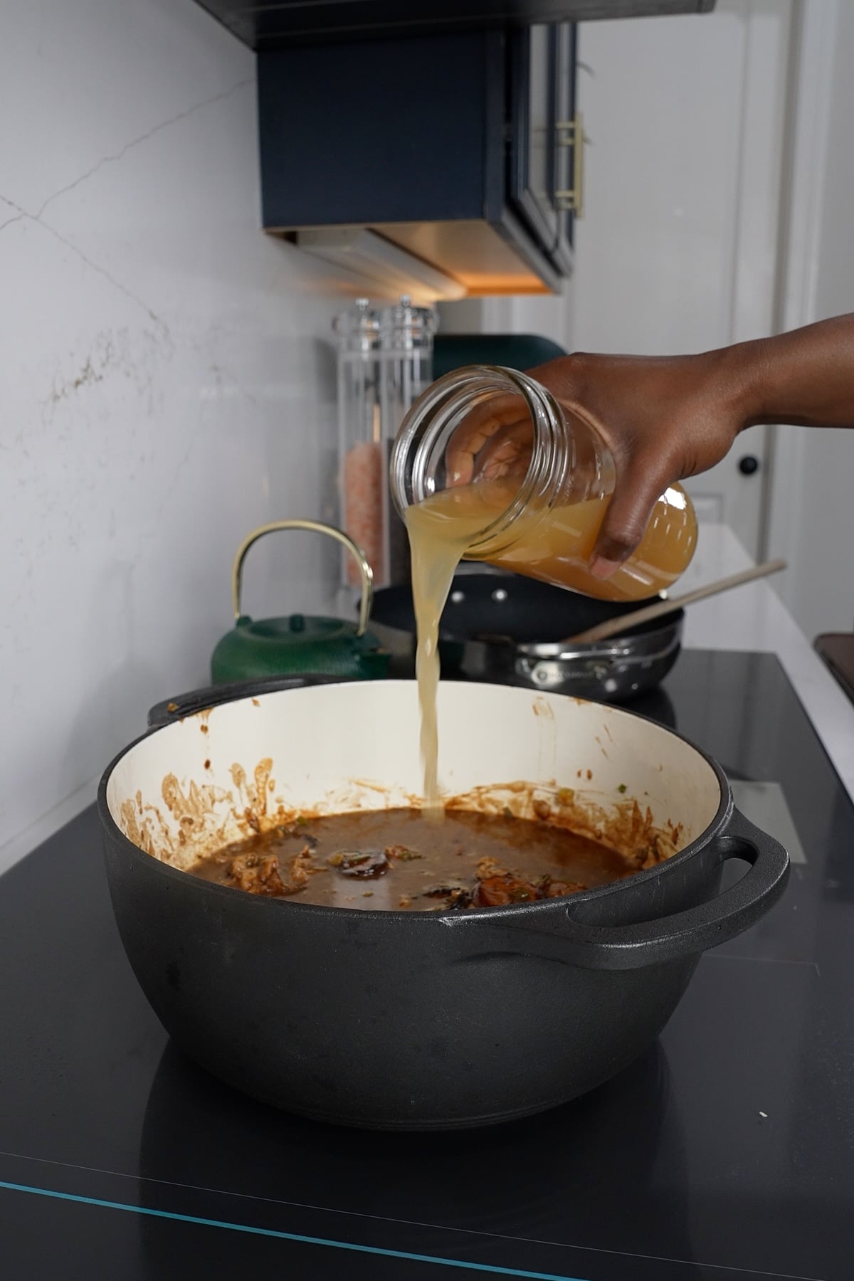 Chicken broth being poured into pot, making gumbo.
