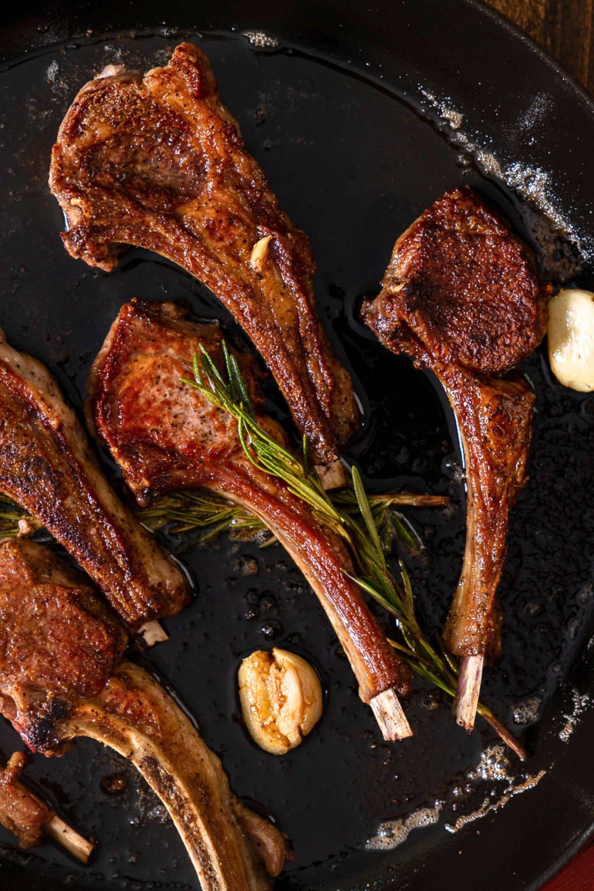 Lamb chops in skillet with rosemary and garlic. 