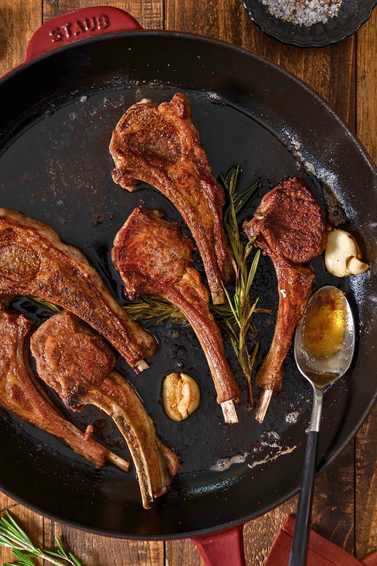 Lamb chops and skillet with rosemary and garlic, and spoon with butter sauce on it