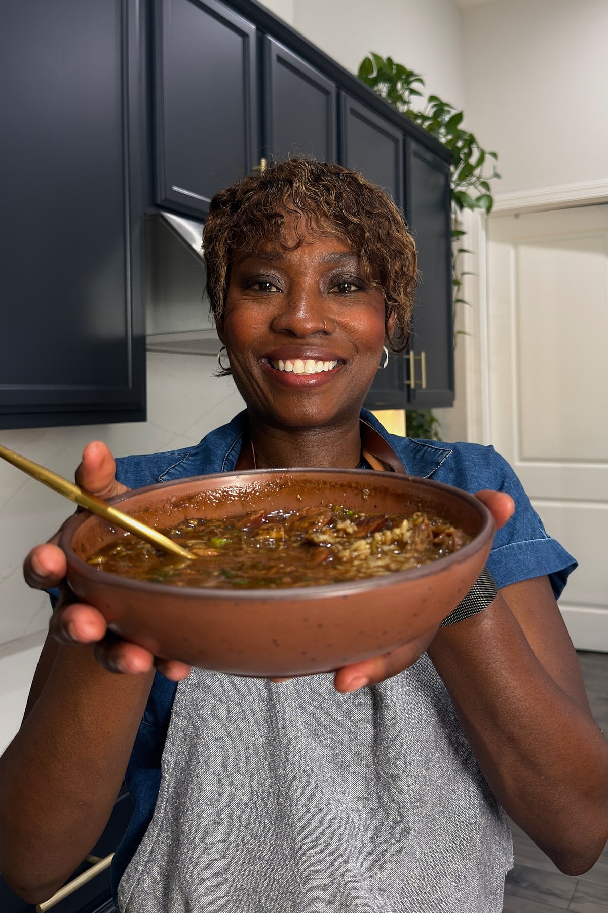 Tanya holding a bowl of gumbo, smiling at the camera.