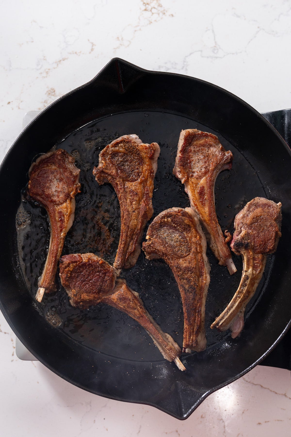 Lamb chops cooking in skillet.