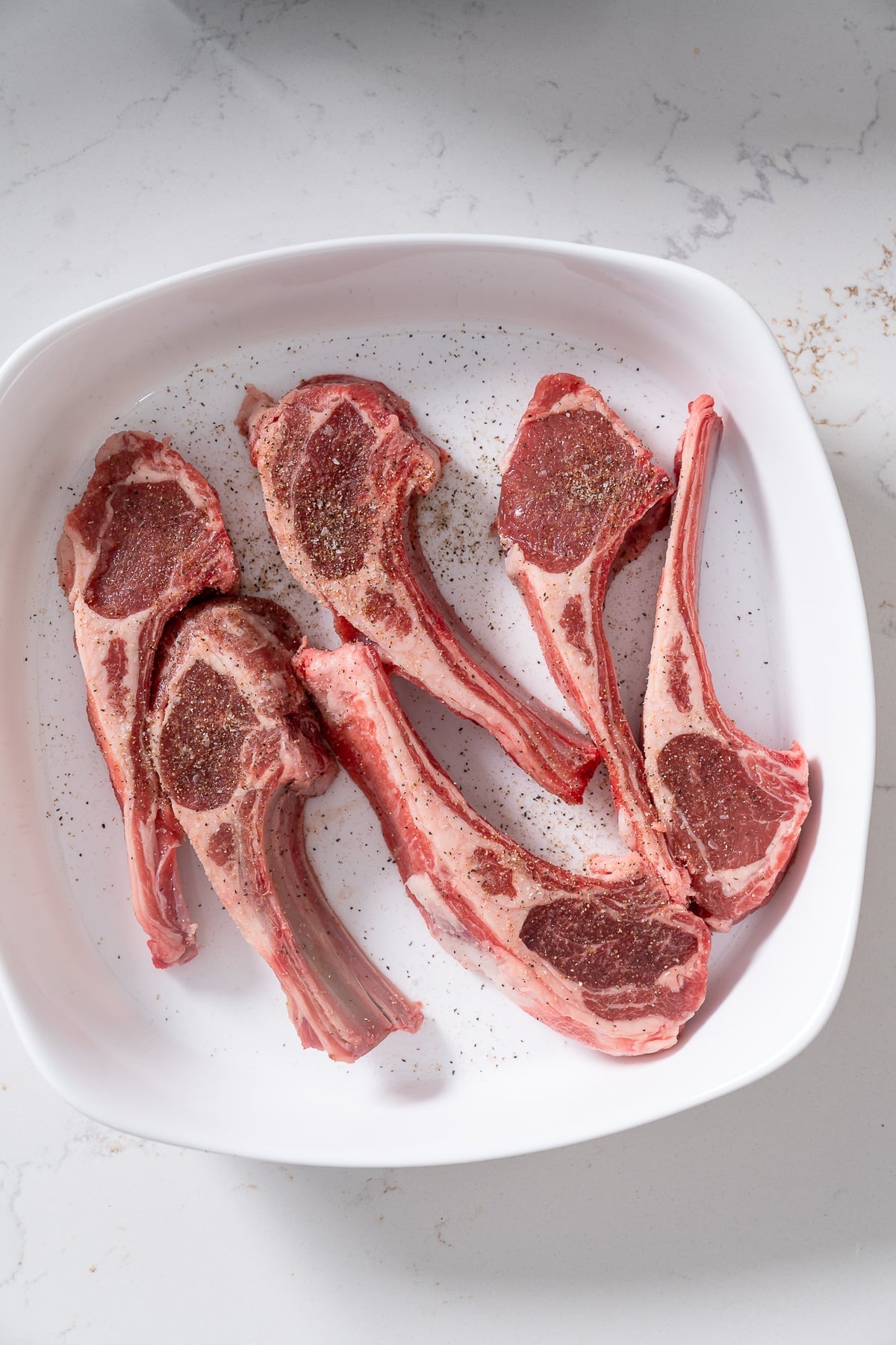 Lamb chops that have been seasoned with salt, black pepper, and cumin.