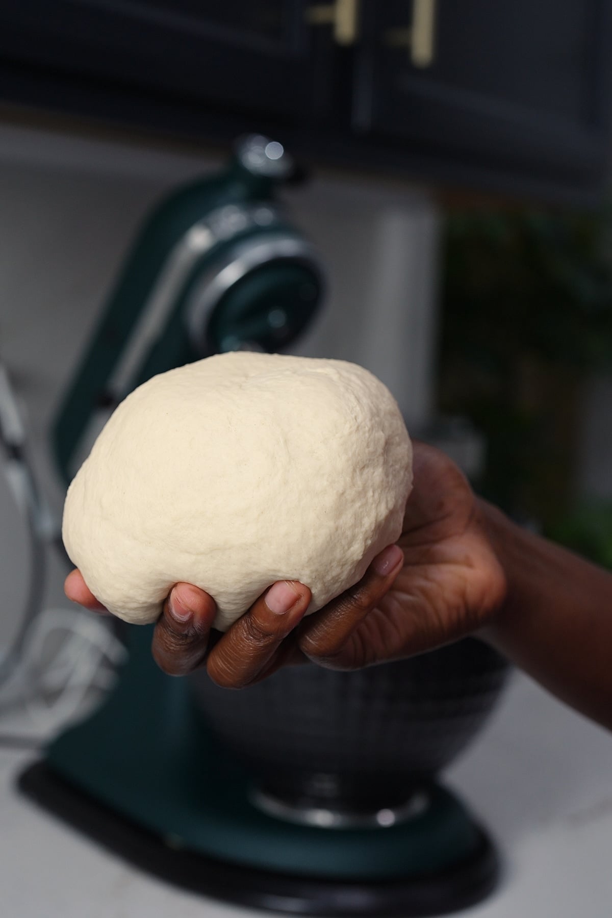 hand holding dough after mixing in bowl