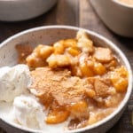 peach cobbler in a bowl with vanilla ice cream on the side