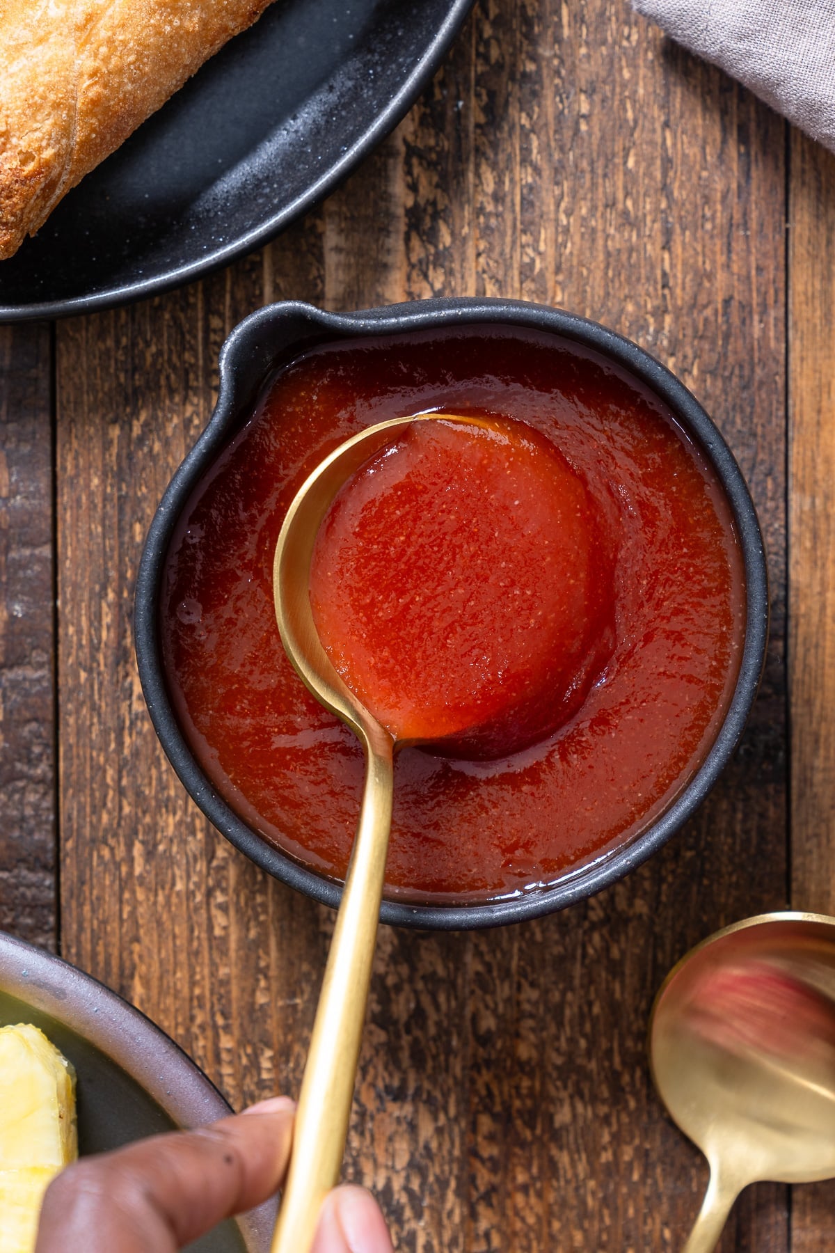 spoon lifting out sweet and sour sauce out of serving dish