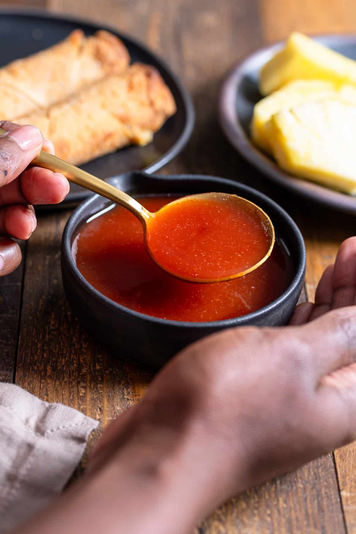 hand holding up sweet and sour sauce with spoon