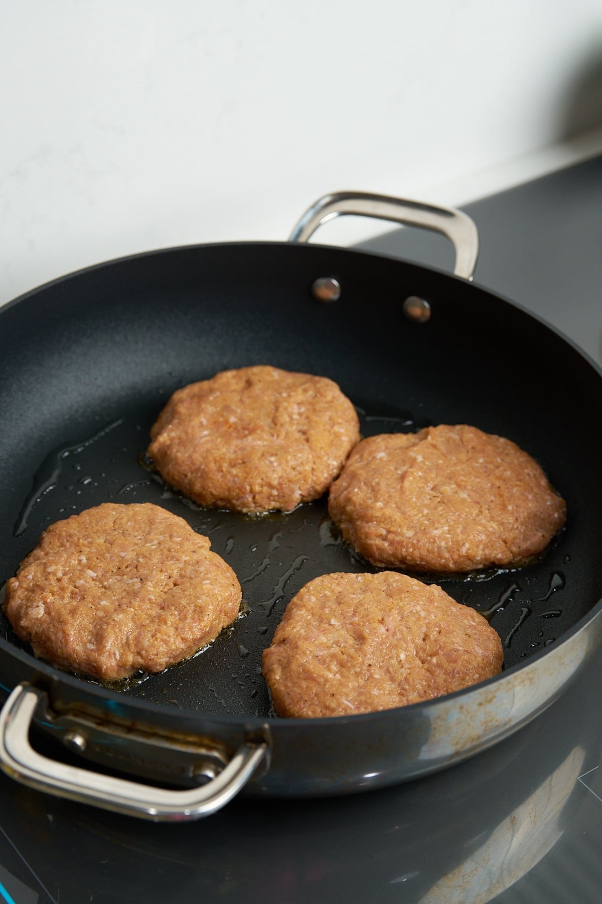 raw turkey burger patties in skillet