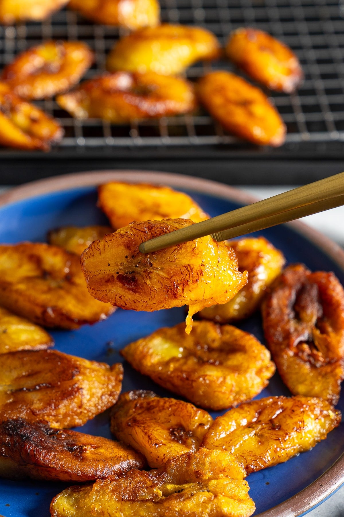 tongs picking up fried plantains