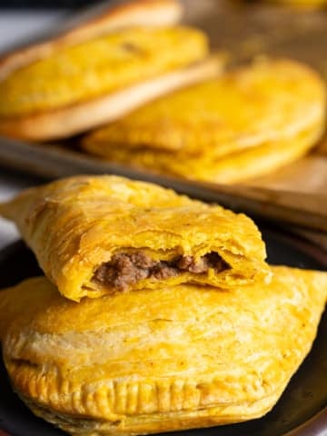 jamaican beef patties on plate, one open to see the inside
