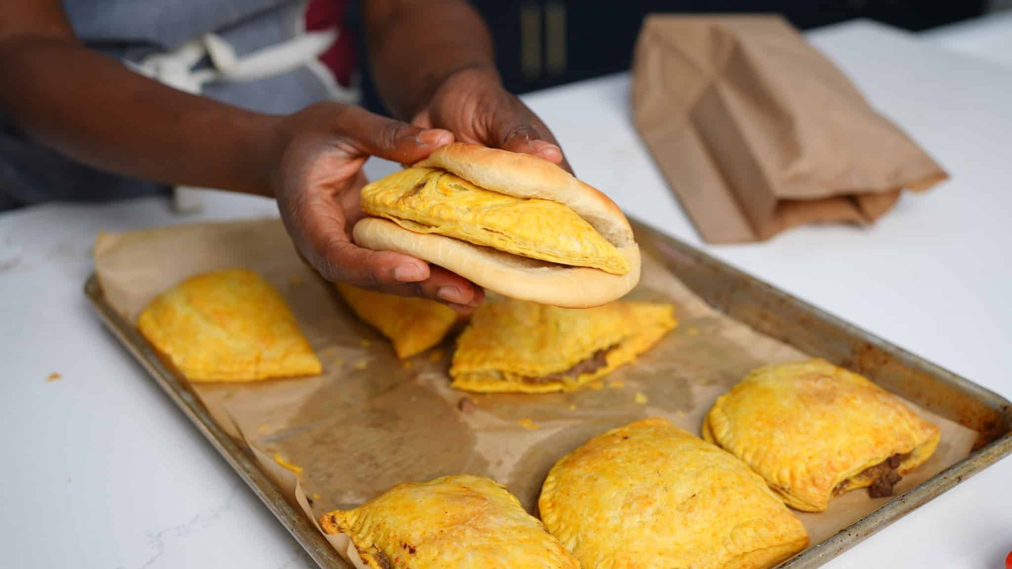 tanya holding beef patty in hand with coco bread