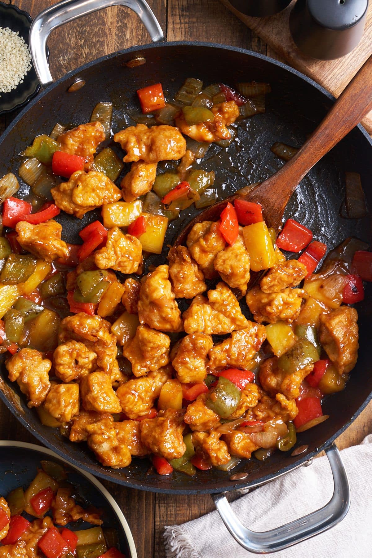 sweet and sour chicken in skillet with spoon scooping it