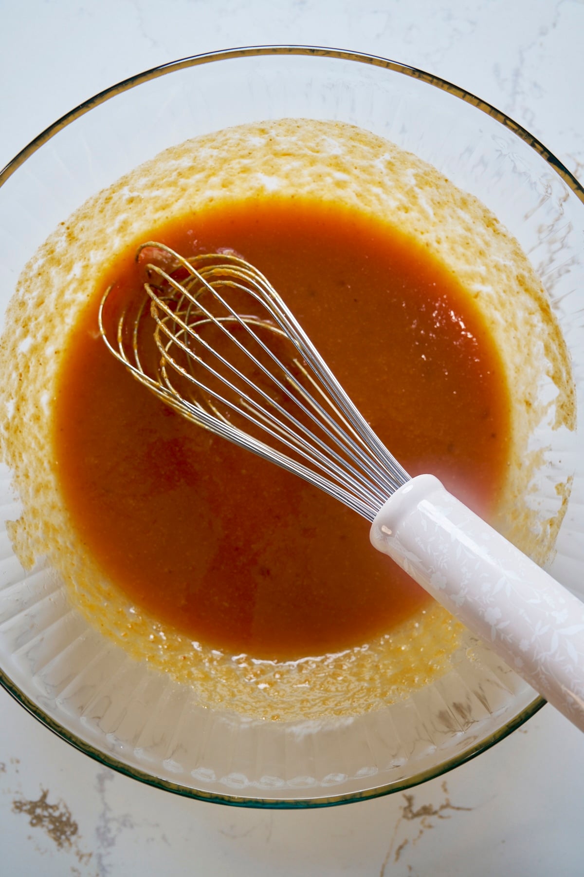 Pumpkin purée, sugar, oil, and eggs whisked smooth in a glass mixing bowl
