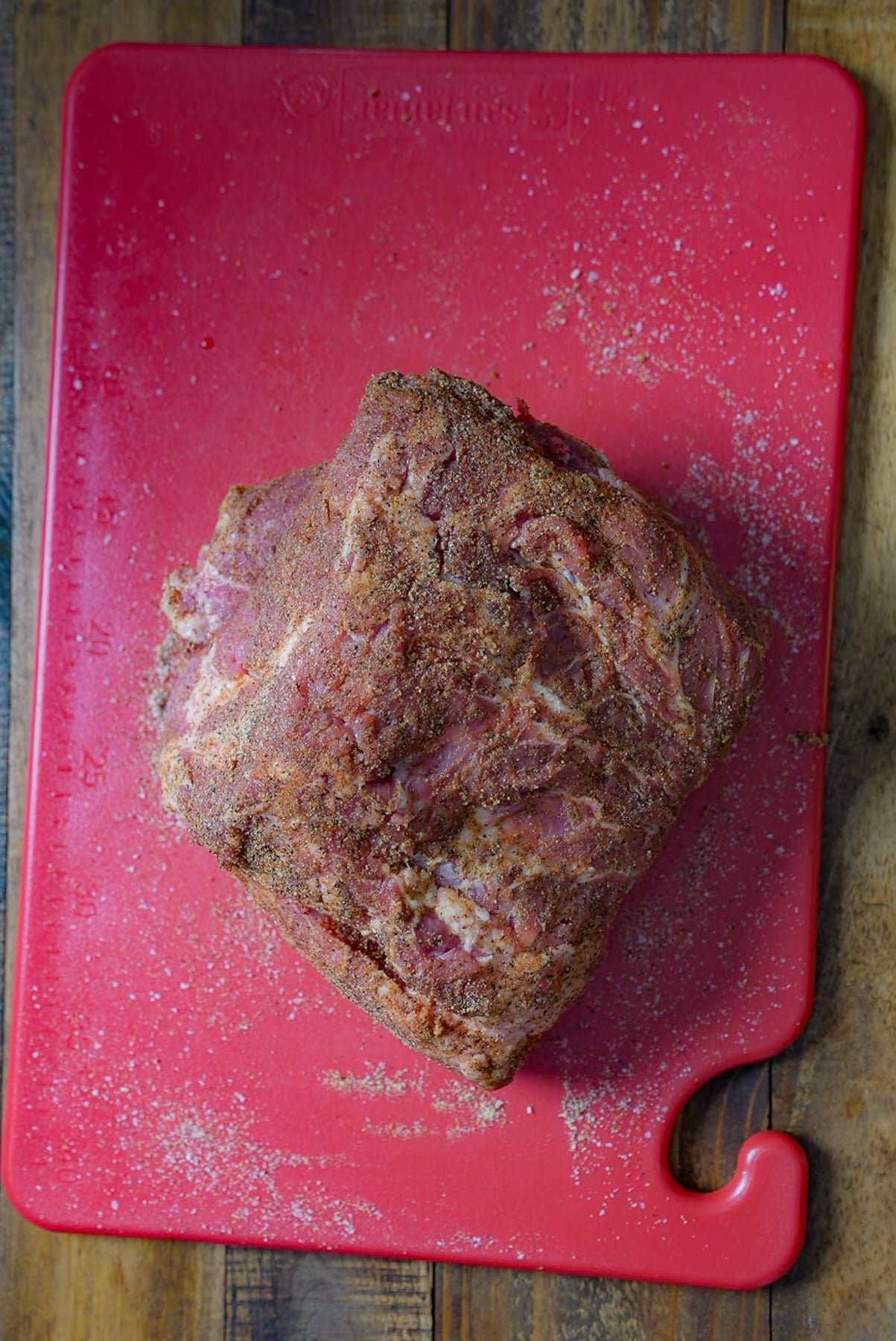 Raw pork butt on a red cutting board