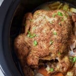 cooked whole chicken in slow cooker insert with parsley sprinkled on top