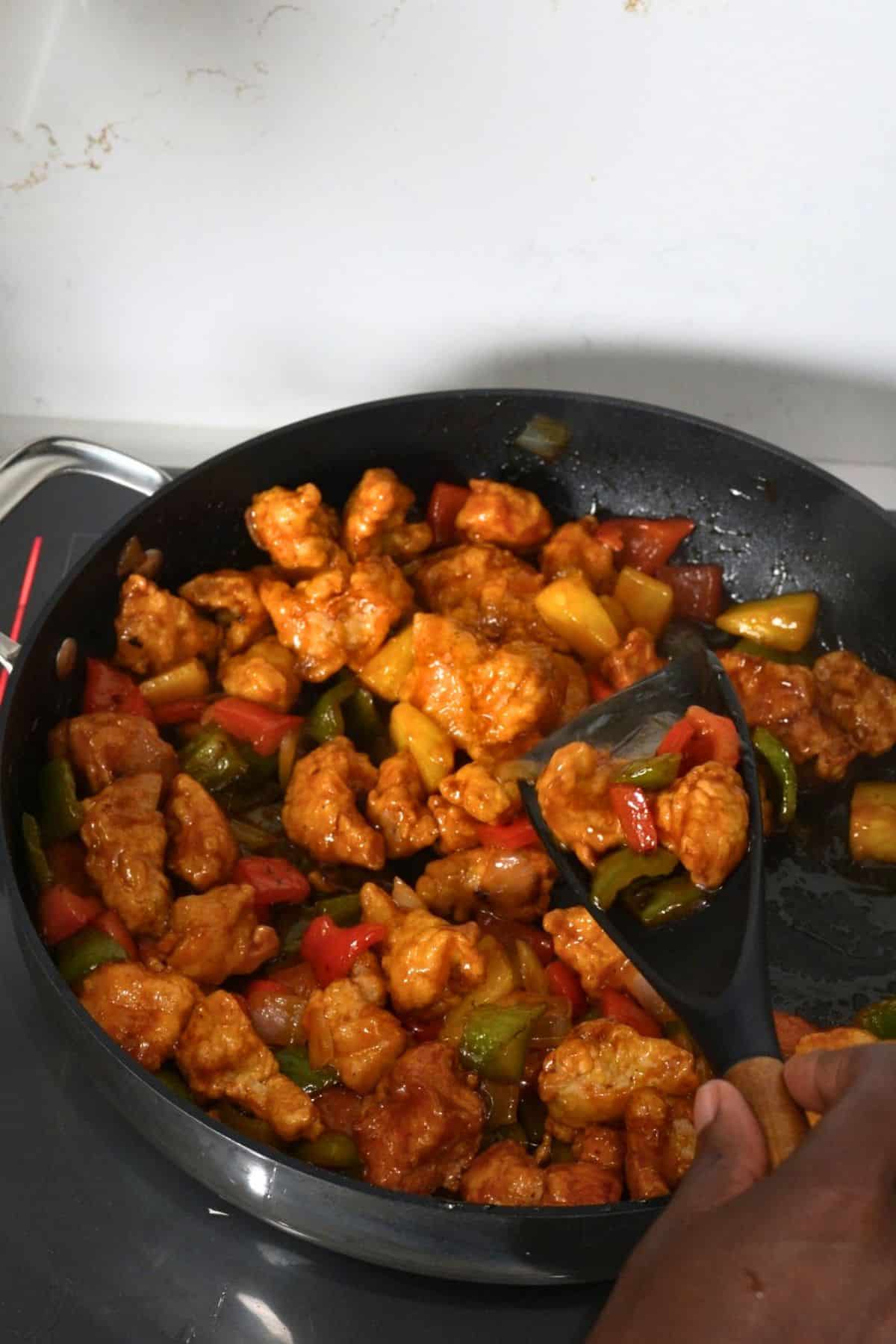 sweet and sour chicken in skillet with spatula