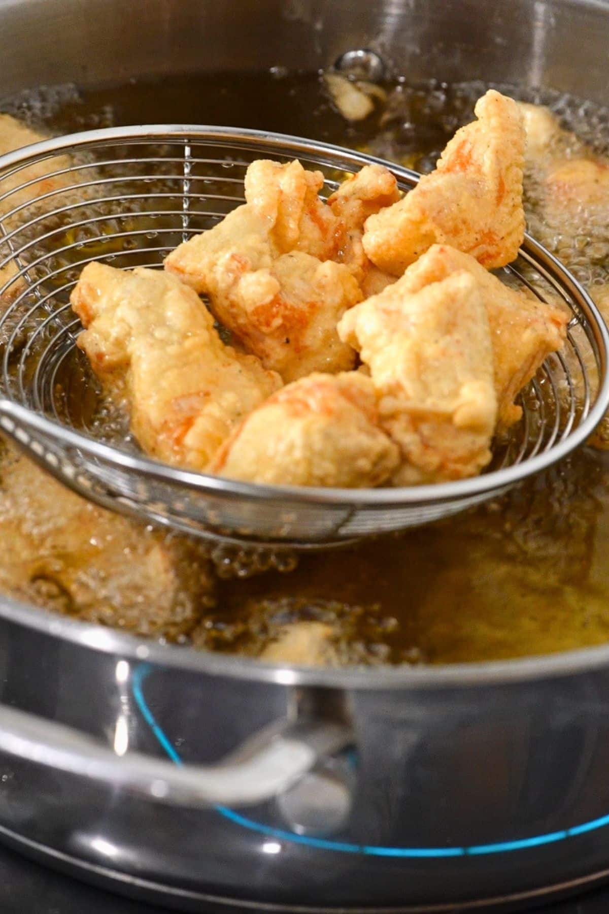 chicken frying in oil, getting lifted out of oil
