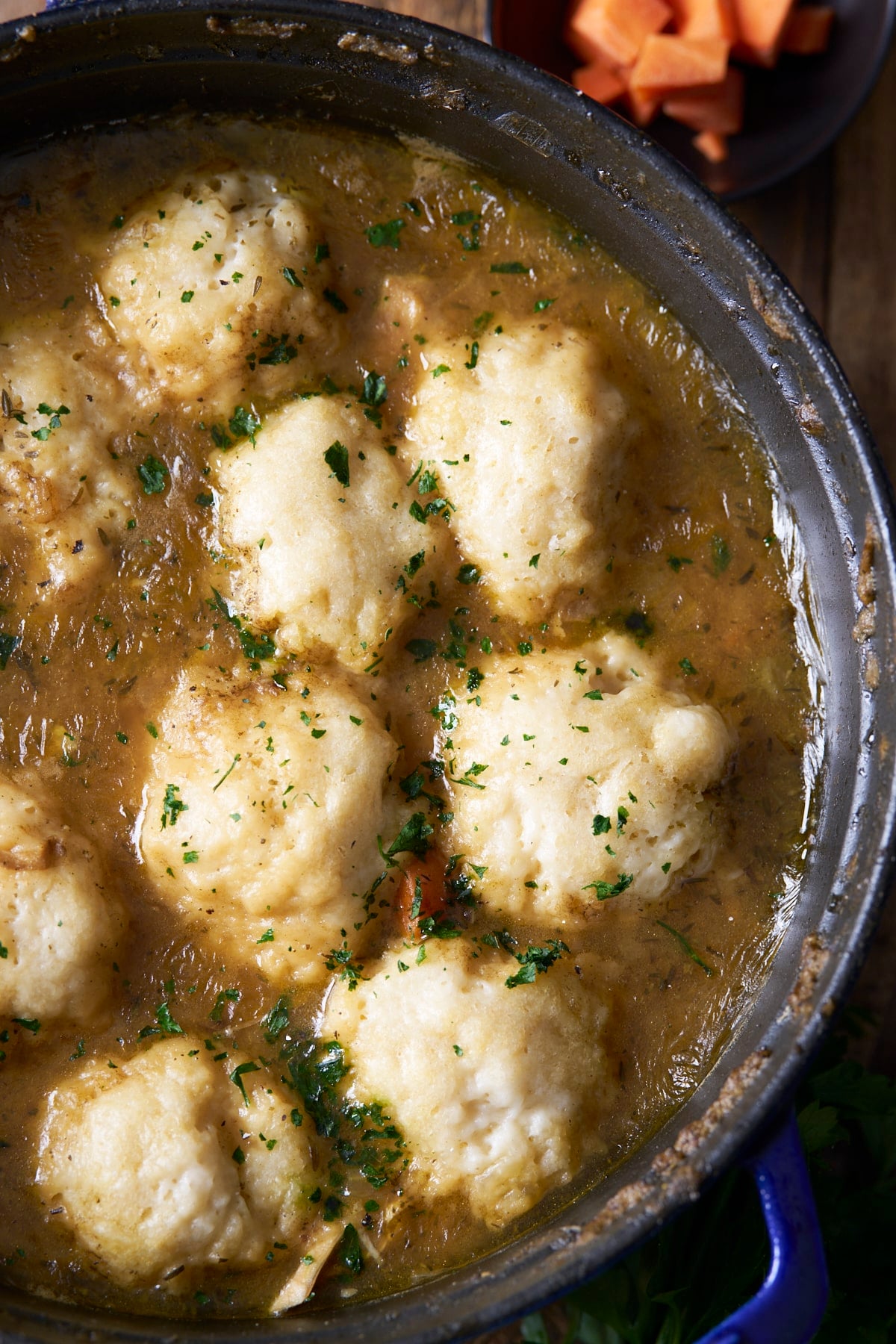 Overhead view of finished chicken and dumplings in a blue Staub Dutch oven