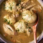 Overhead bowl of chicken and dumplings with a wooden spoon