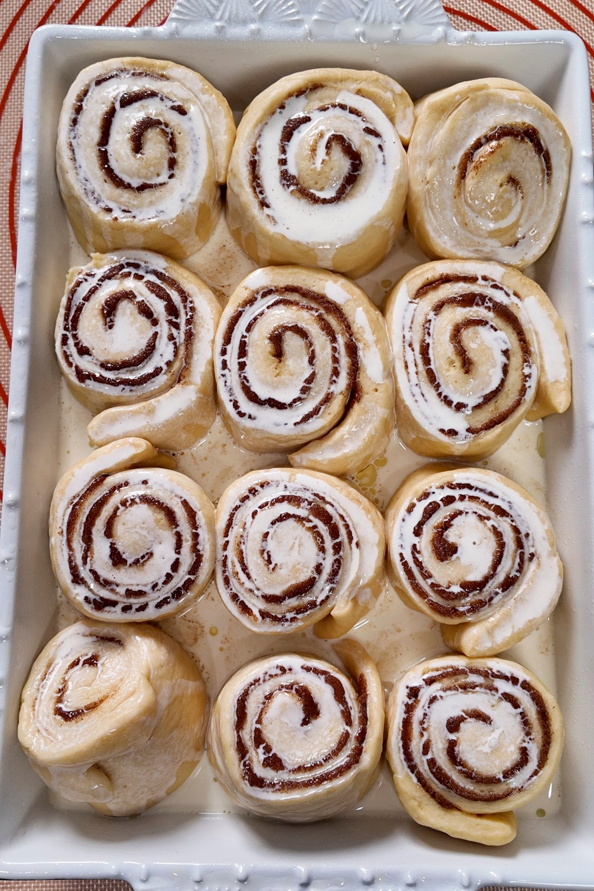 heavy cream poured on cinnamon rolls in baking pan