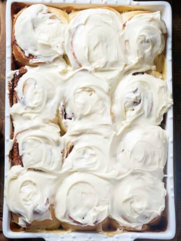 Freshly baked cinnamon rolls covered in cream cheese icing.