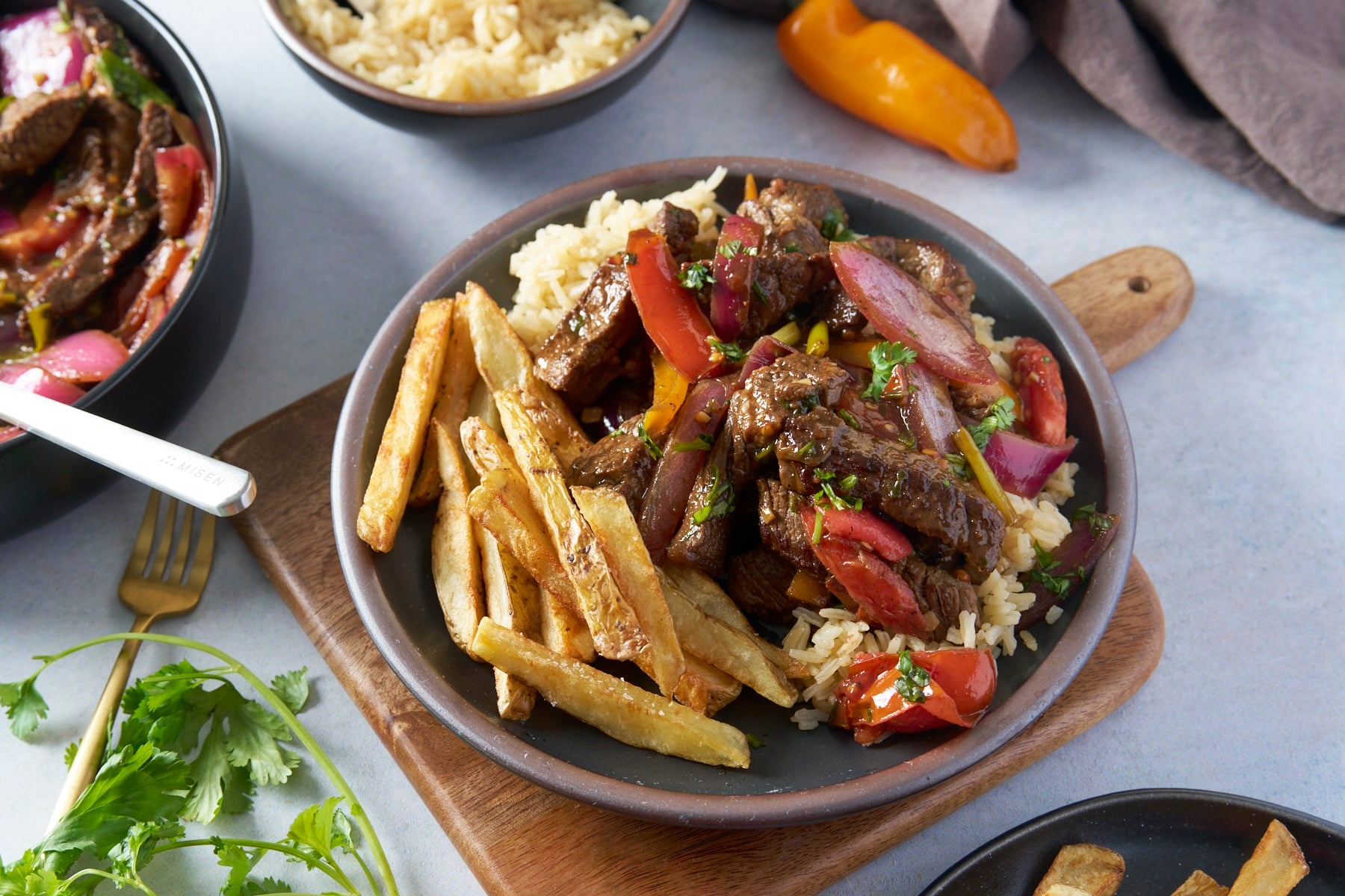 plated lomo saltado with tender beef, charred onions, and crispy fries"