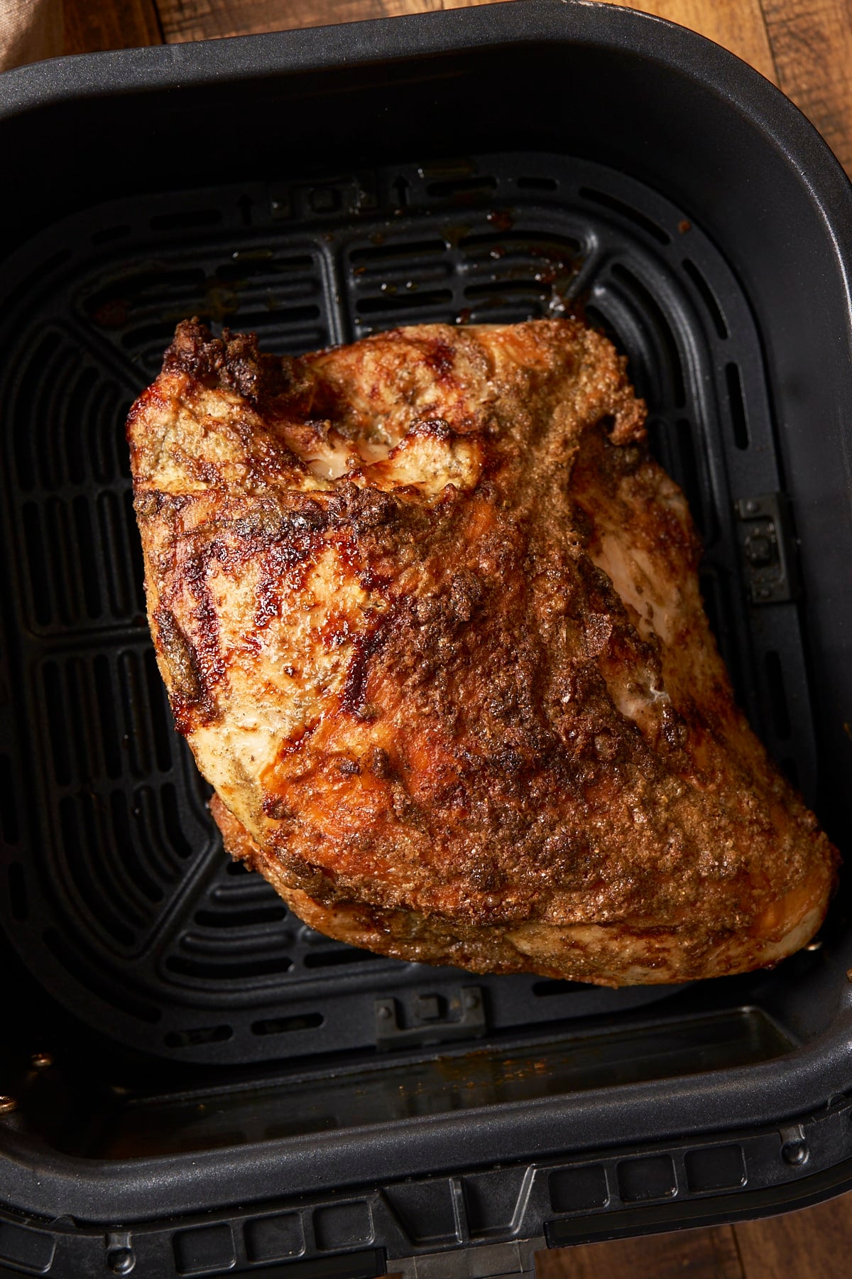 Cooked turkey breast with deep golden brown, crisp skin in the air fryer basket