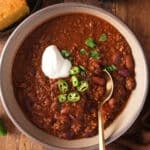 beef chili in bowl with toppings and spoon in it