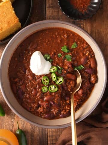 beef chili in bowl with toppings and spoon in it