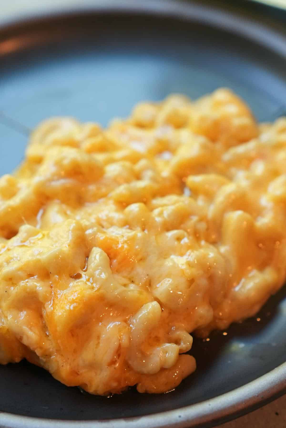 A serving of creamy baked mac and cheese on a dark plate.