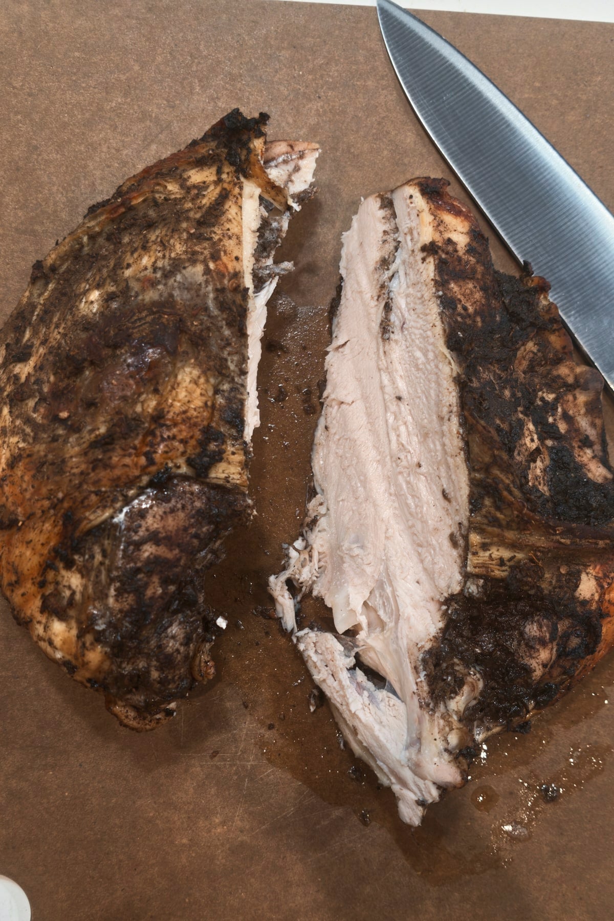 A knife beside turkey breast meat just cut away from the bone, showing the white meat inside.