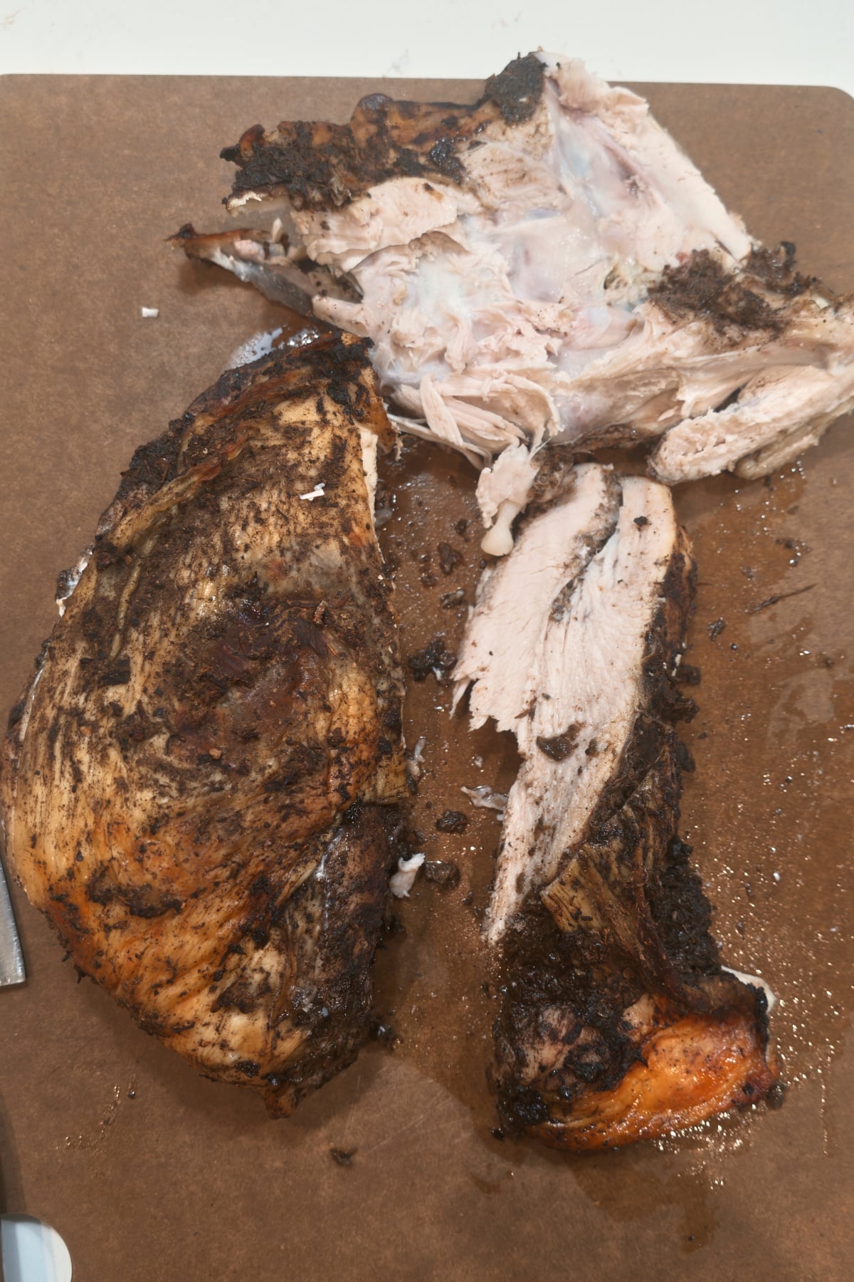 Turkey breast meat lifted off the bone in one piece on a cutting board, with the bone behind it.