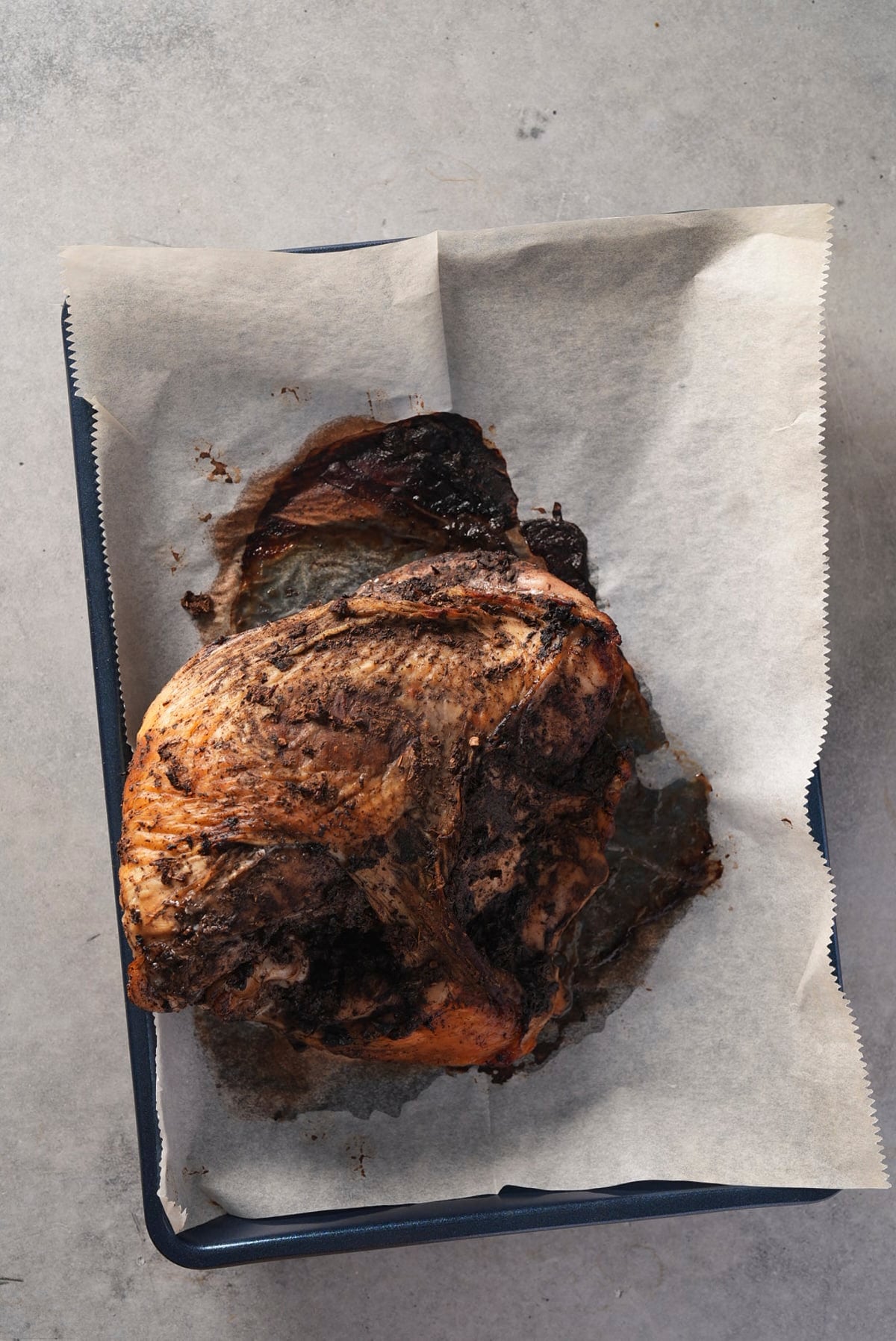 Roasted turkey breast with a dark, crusted jerk coating on a parchment-lined baking sheet.