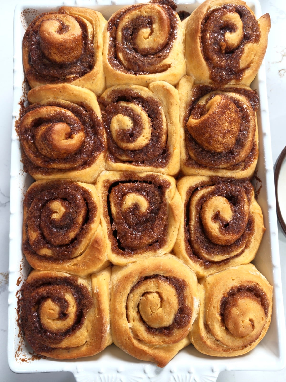 Golden brown baked rolls in the baking dish, before the glaze goes on.
