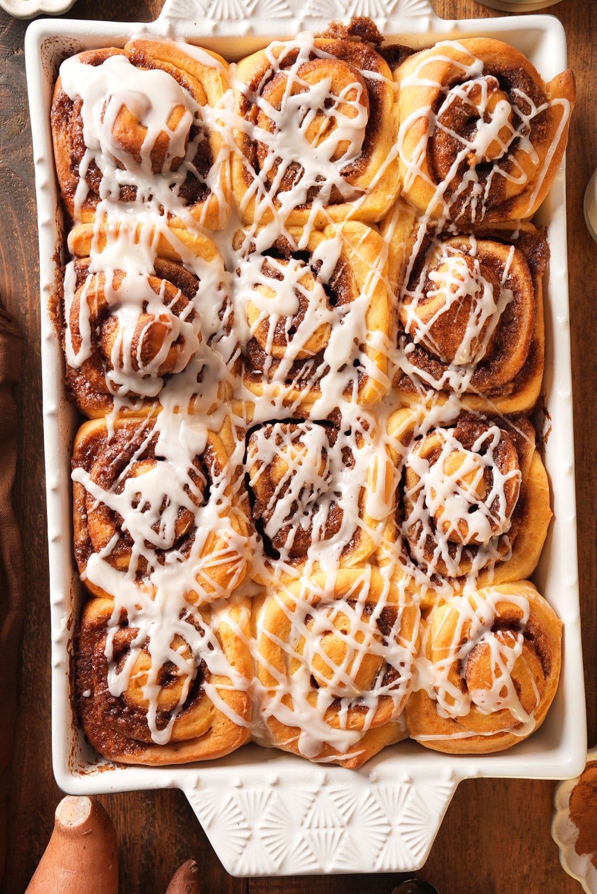 A full pan of twelve glazed sweet potato cinnamon rolls showing the cinnamon swirls.